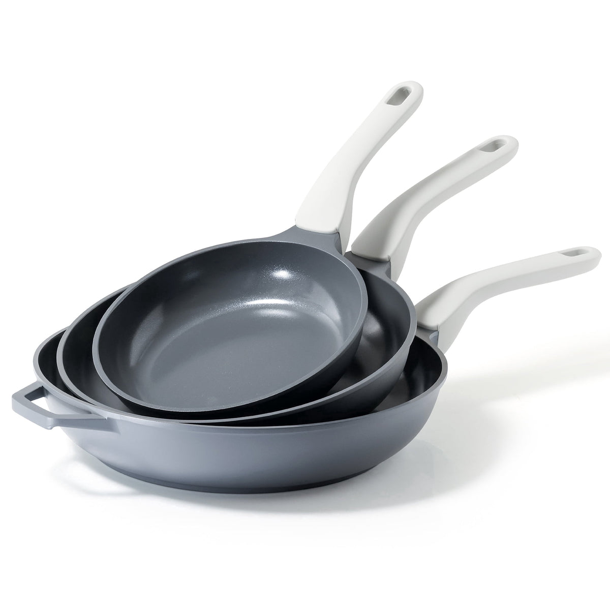 Three gray frying pans with light gray handles, stacked together.